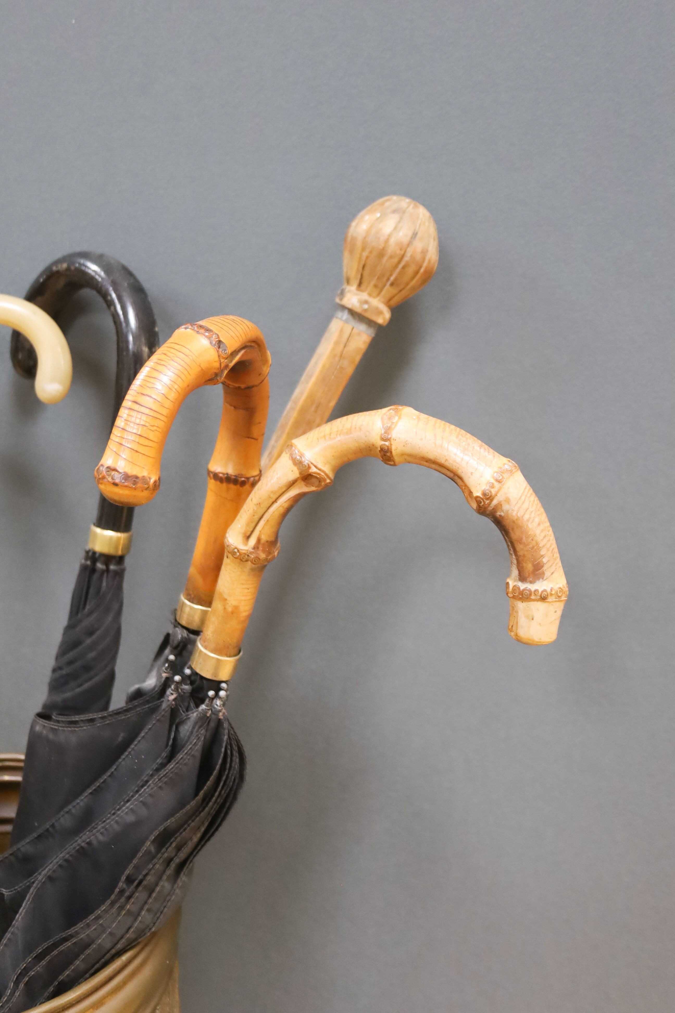A cylindrical repousse brass stick stand, with walking sticks, parasols, etc.